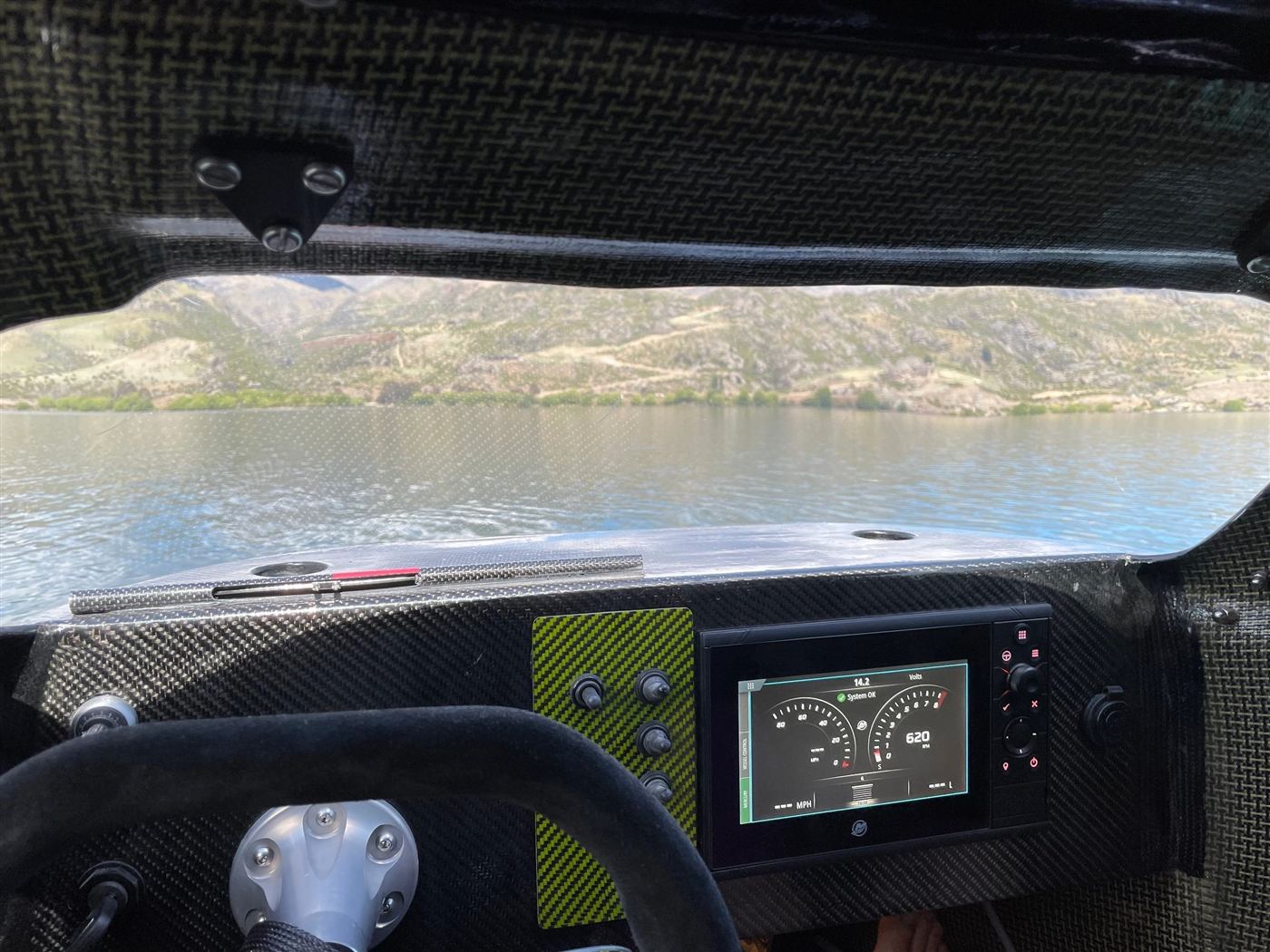 View from inside the F1 Super Boat cockpit: carbon-fibre dash, steering wheel and Lake Dunstan ahead