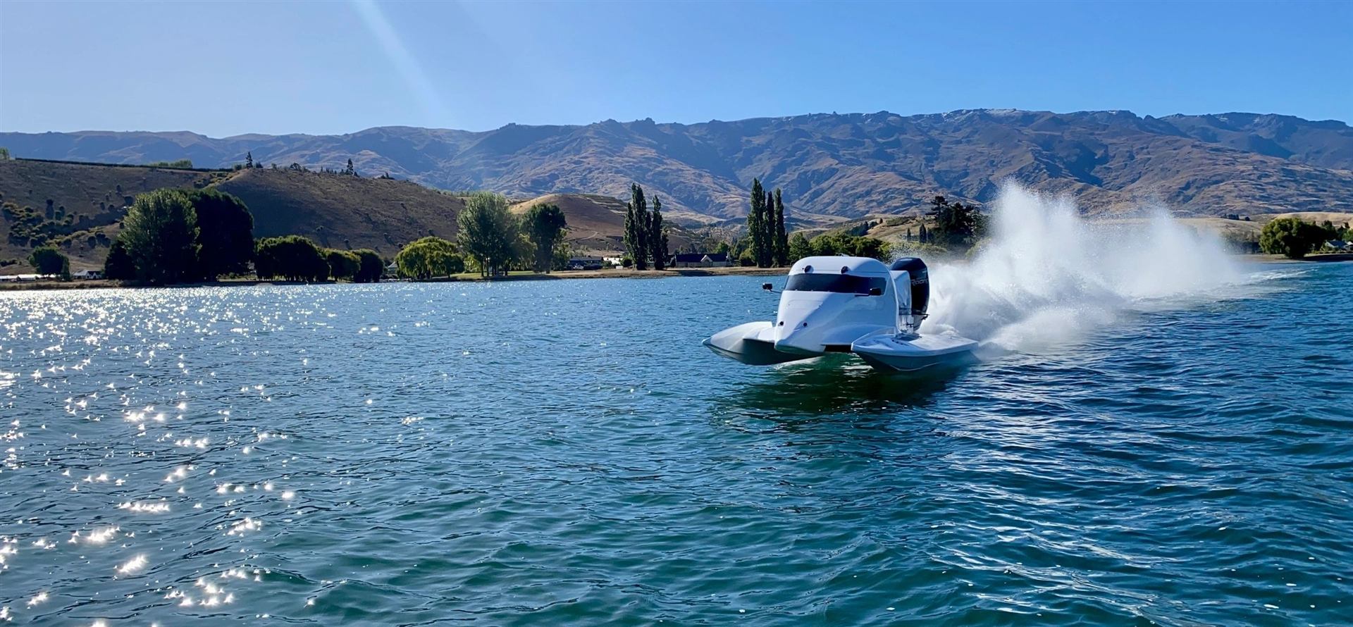 Speed boat ride on Lake Dunstan, Cromwell: F1 Super Boat throwing a huge spray with Central Otago mountains behind