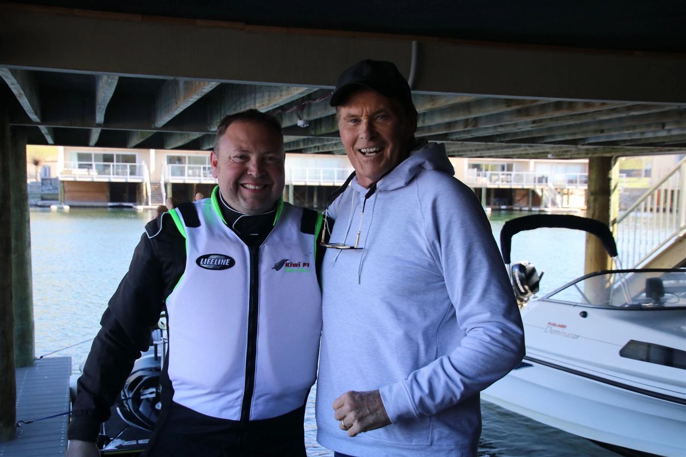 F1 Super Boat pilot in race suit with a guest at the boat shed